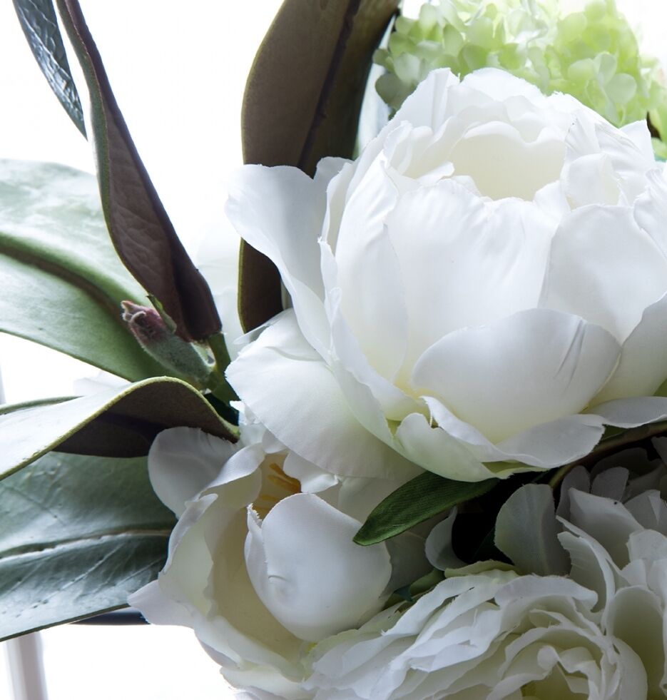 Close-up of a bouquet featuring white peonies and glossy green leaves, with soft lighting highlighting the delicate petals.