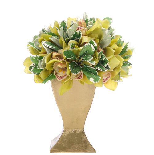 A decorative bouquet of green and yellow flowers with leafy accents is arranged in a gold vase. The flowers are lush and tightly packed, giving a vibrant and full appearance. The vase has a classic, elegant shape.